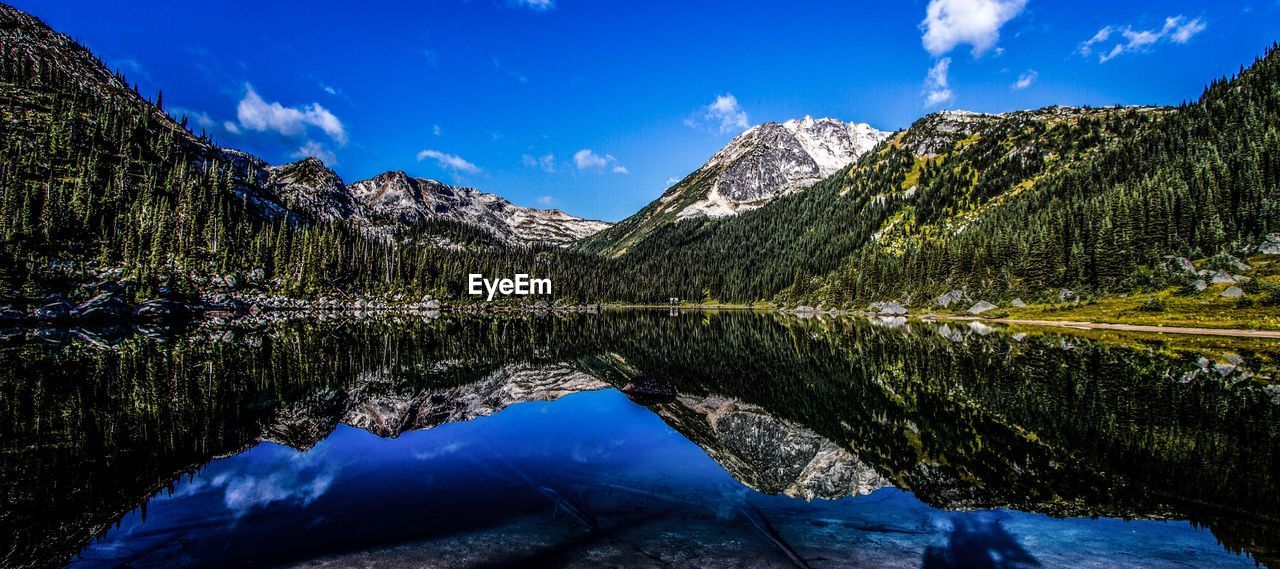 Scenic view of lake and mountains against blue sky