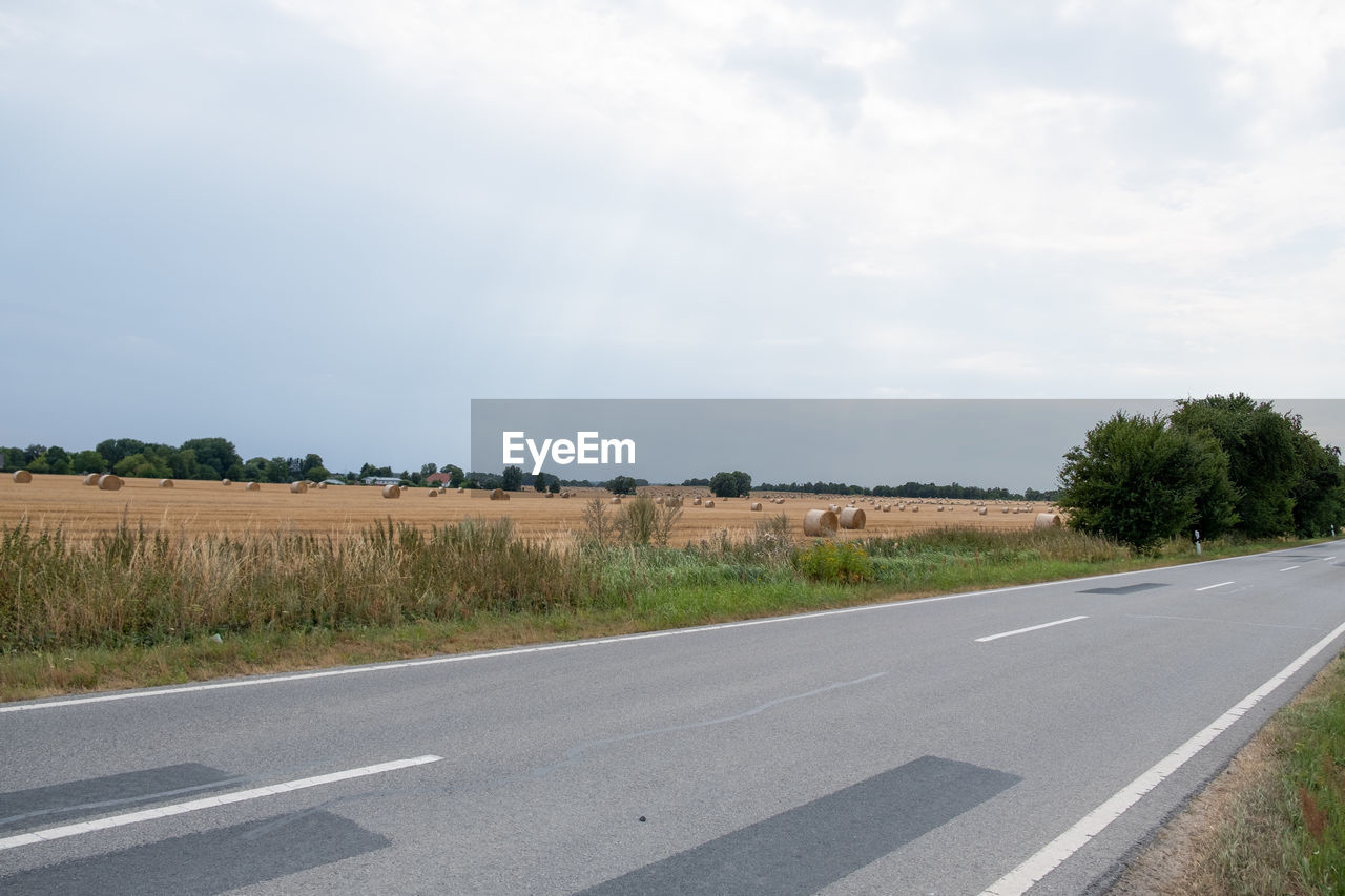 Road by field against sky