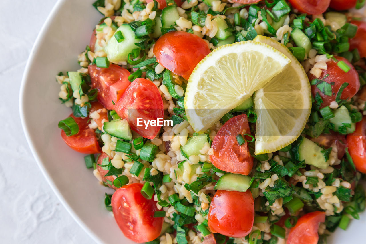 Tabbouleh salad on a dish on light background. lebanese cuisine. top view.