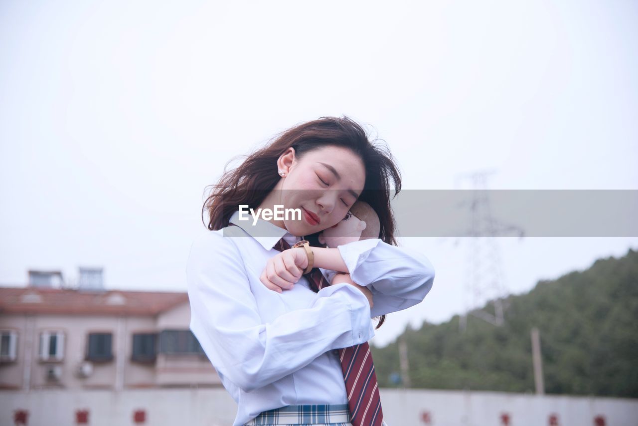 Low angle view of woman embracing toy while standing against sky