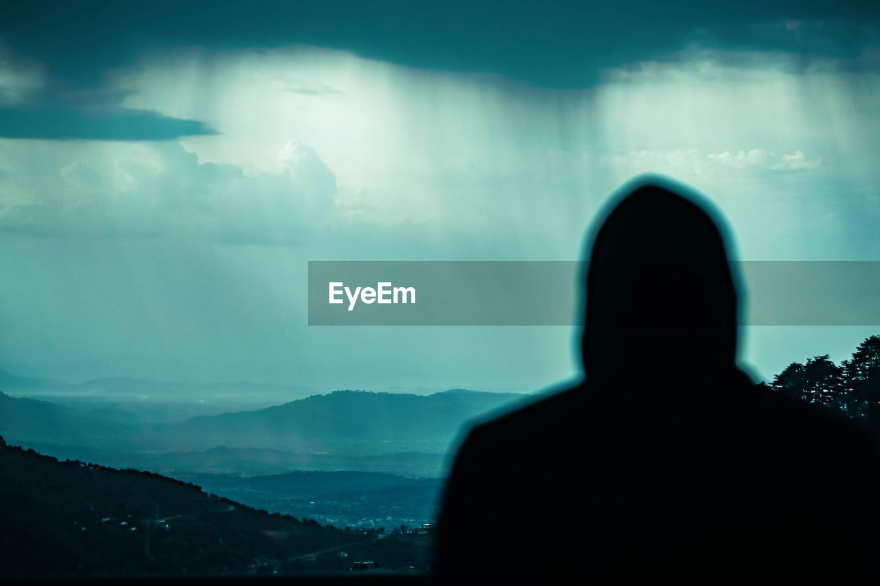 Rear view of silhouette man looking at mountains against sky