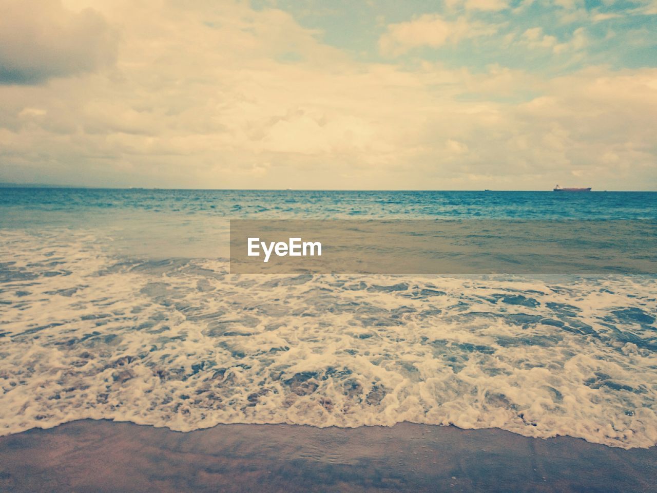 Scenic view of beach against cloudy sky at sunset