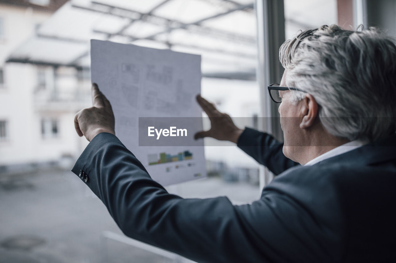 Senior businessman looking at paper at the window