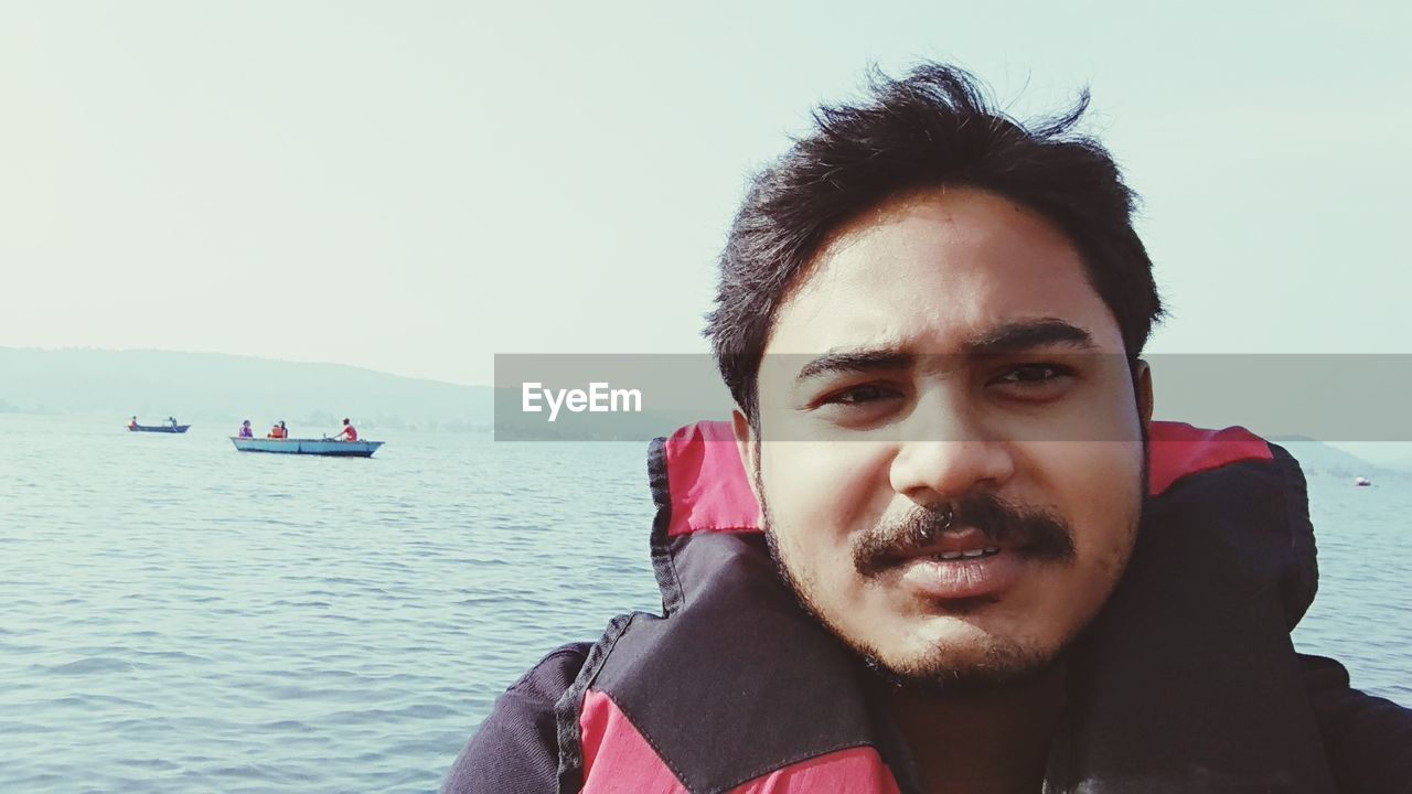 PORTRAIT OF YOUNG MAN SAILING IN LAKE