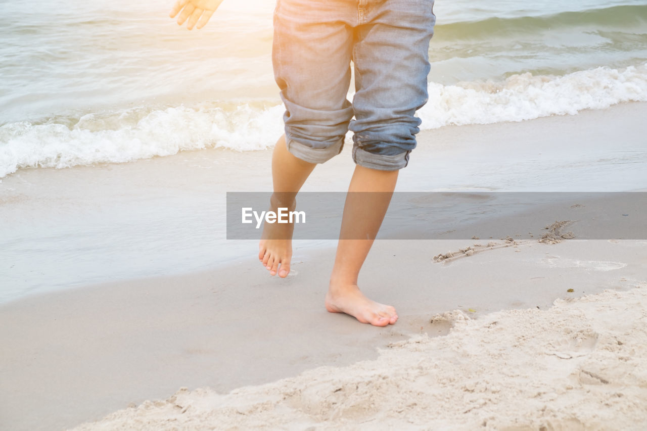 Low section of girl walking at beach