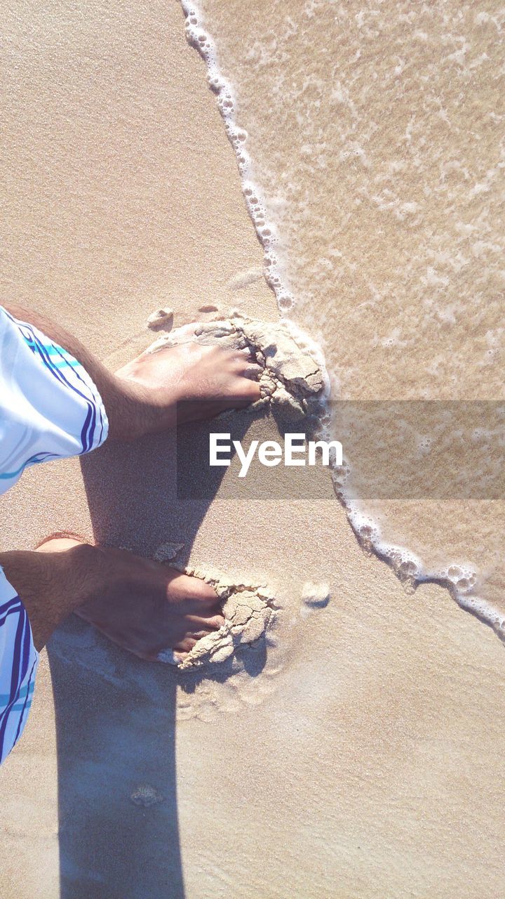 Directly above shot of human feet standing on beach