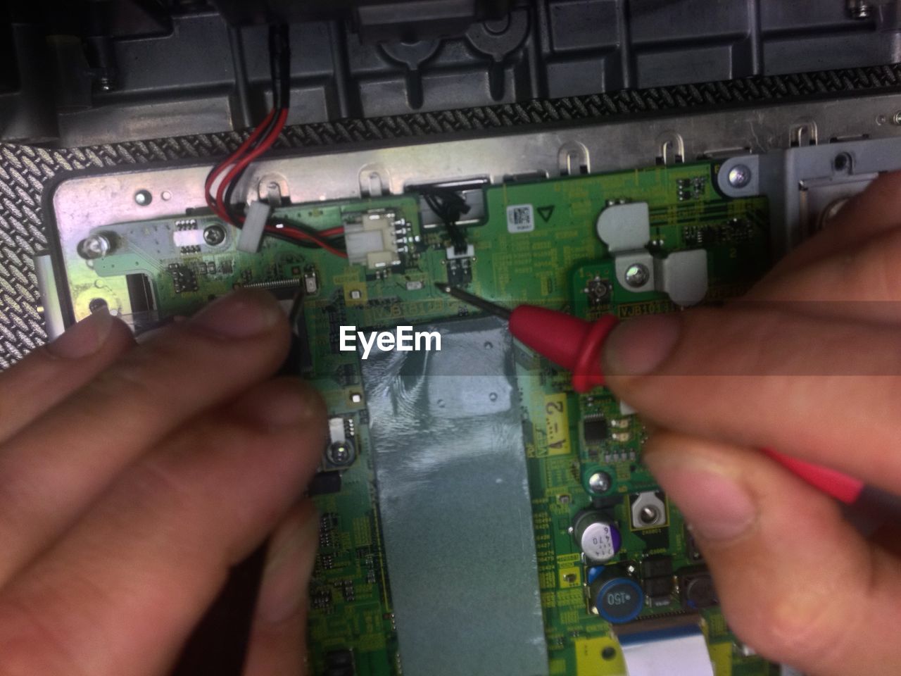 Cropped image of technician testing circuit board with test probe
