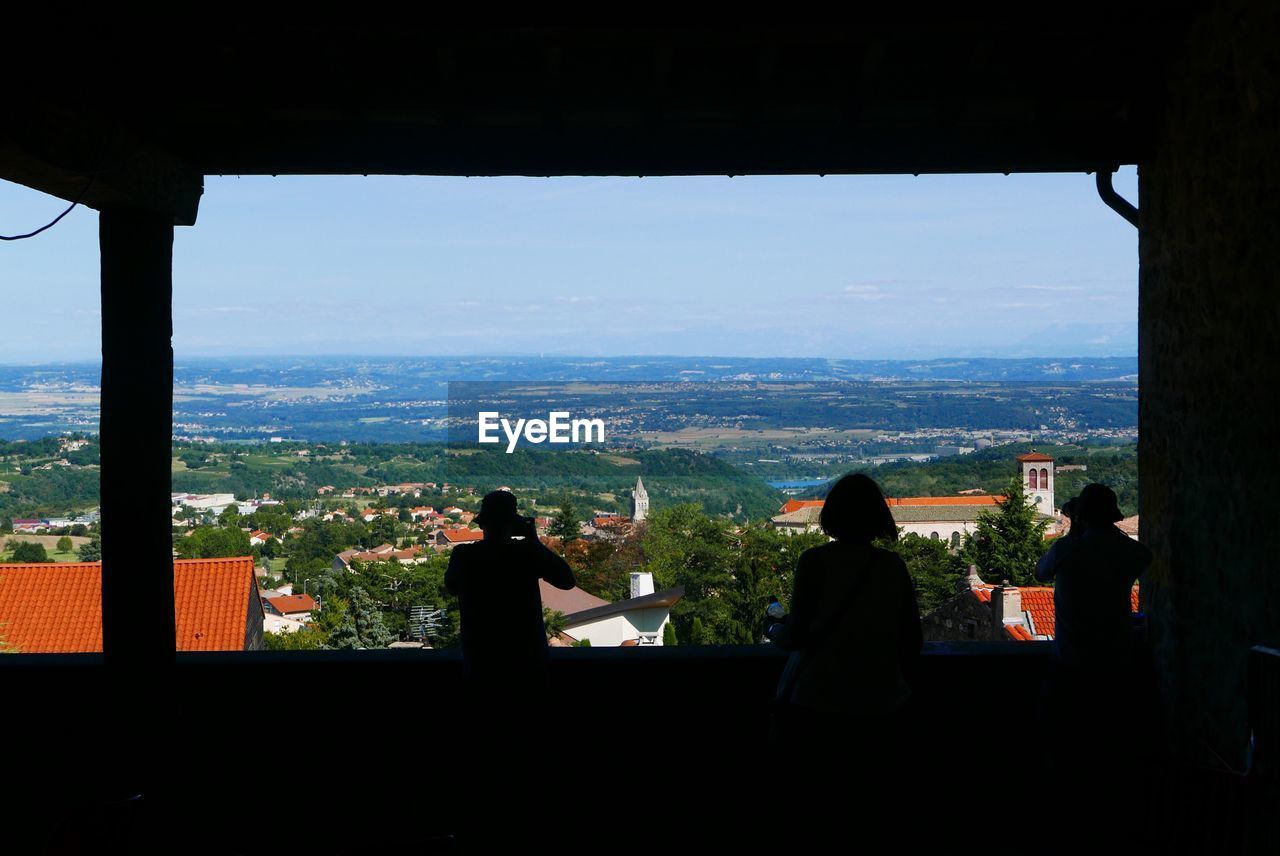 SILHOUETTE OF PEOPLE LOOKING AT CITYSCAPE