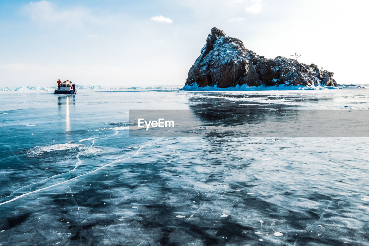 Scenic view of frozen lake and rock against sky