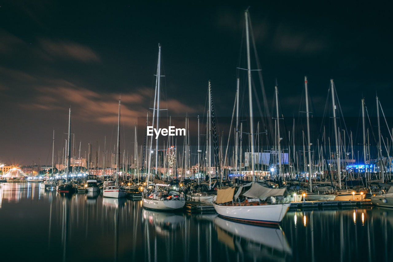 Sailboats moored in harbor at night