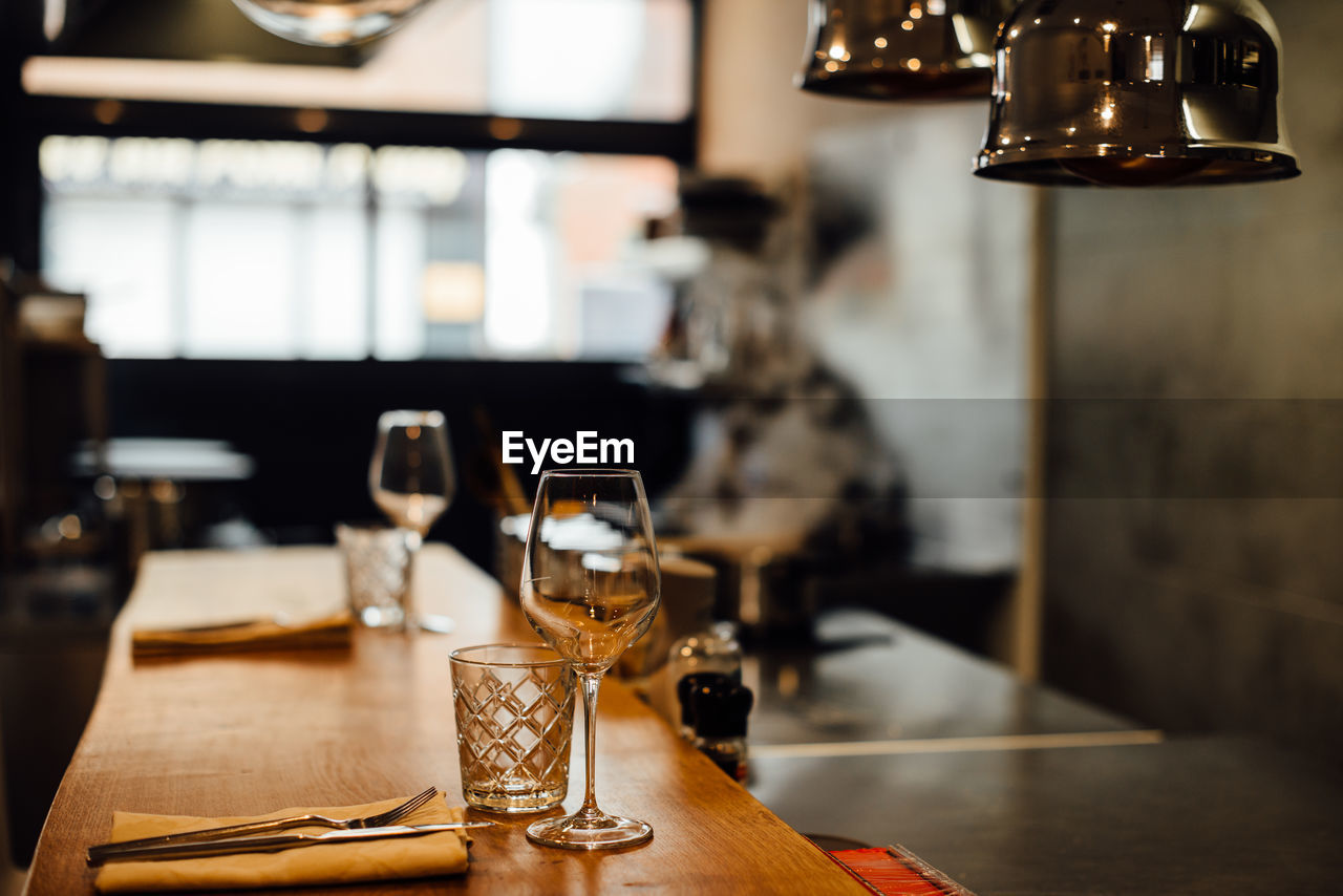 Bar counter with glasses and cutlery at open kitchen restaurant