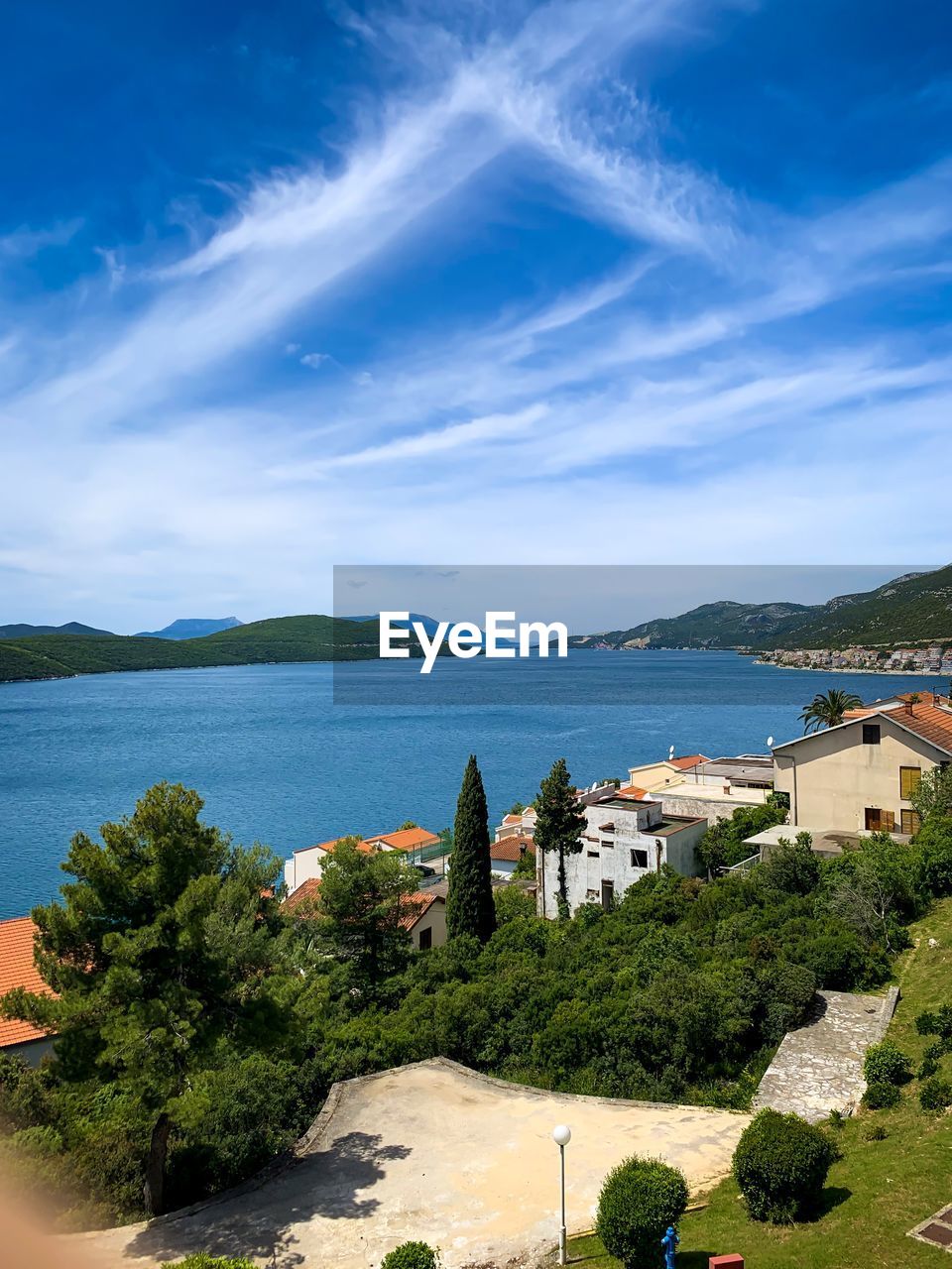 High angle view of buildings by sea against blue sky