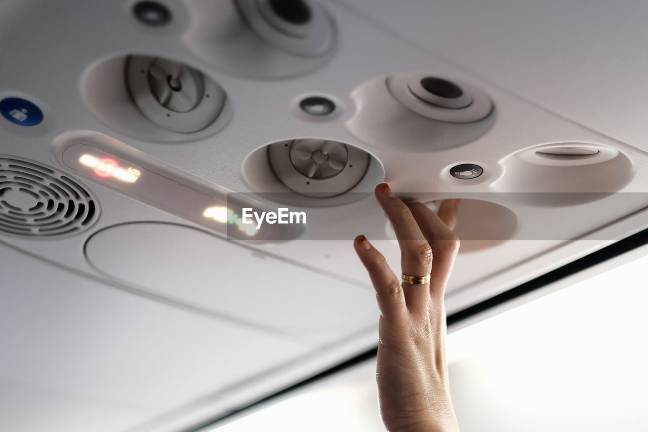 Cropped hand of woman pressing buttons in airplane