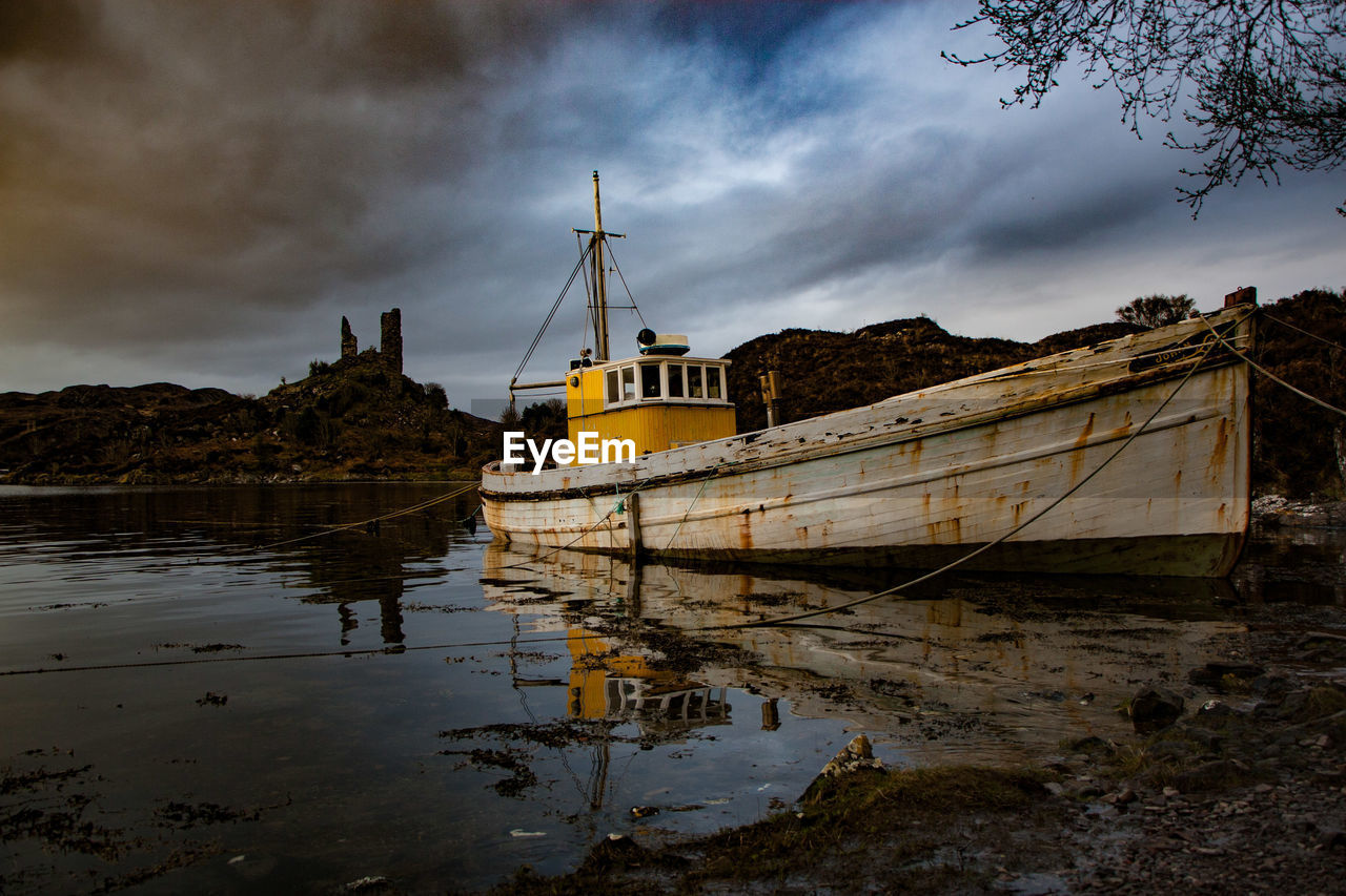 BOATS MOORED AT SEA AGAINST SKY