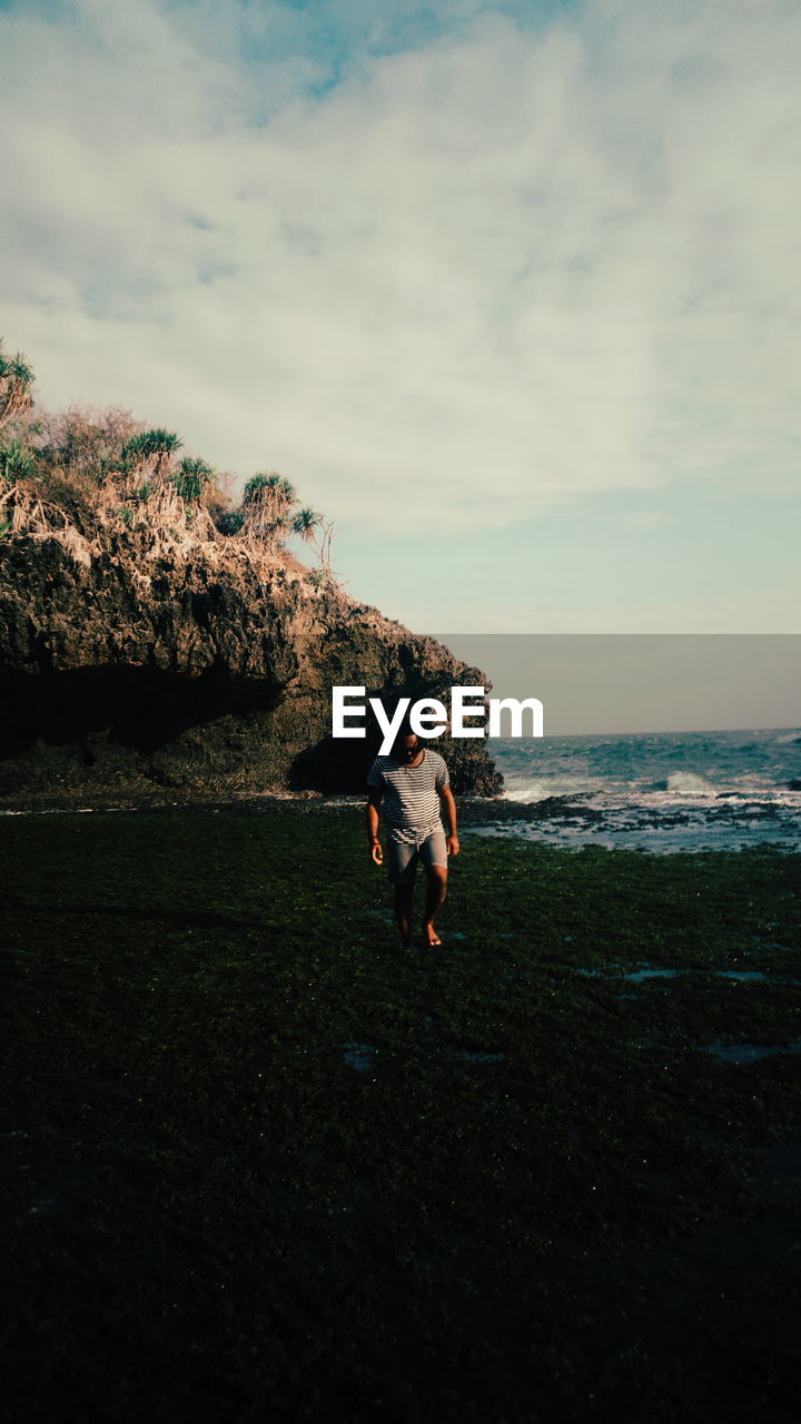 sky, sea, cloud, nature, coast, water, land, beach, ocean, leisure activity, full length, horizon, beauty in nature, lifestyles, sunlight, rock, shore, one person, day, adult, men, morning, scenics - nature, outdoors, plant, blue, women, standing, horizon over water, cliff, body of water, terrain, wave, tranquility, non-urban scene, holiday