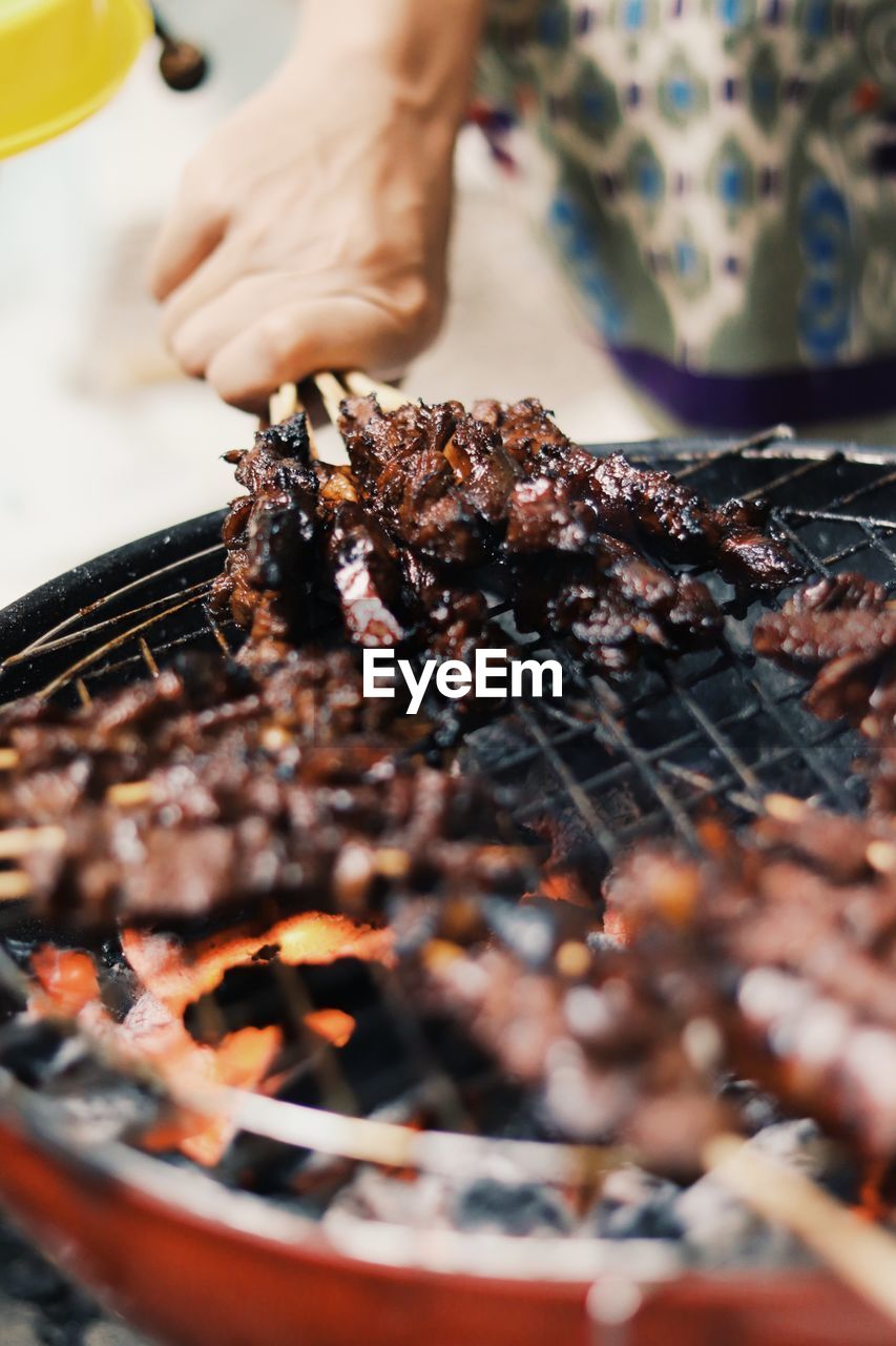 Midsection of person preparing food on barbecue grill