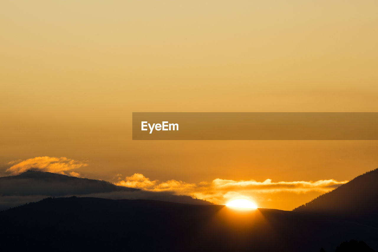 An orange sky at sunrise with mount jumbo on the left