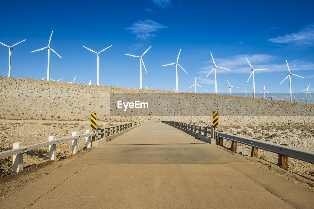 Wind turbines on land against sky