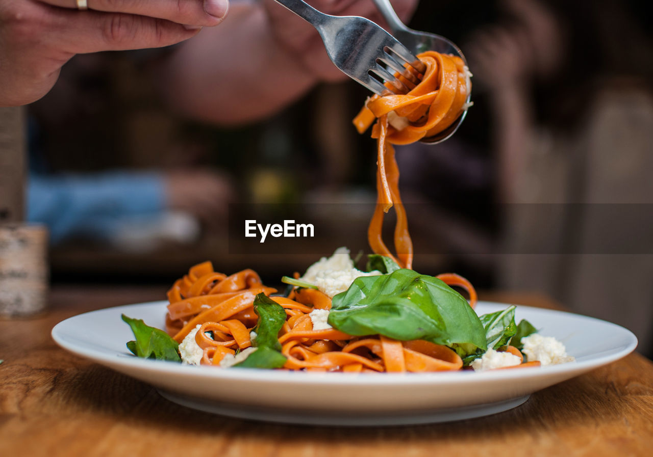 Cropped image of hands having pasta in restaurant