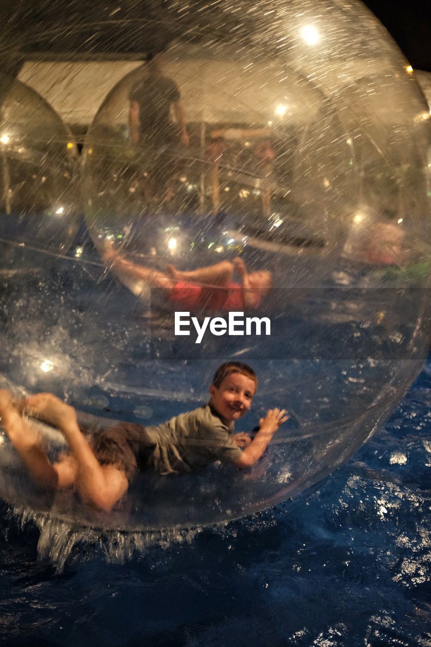 Boy in zorb ball floating on water at gage county fair during night