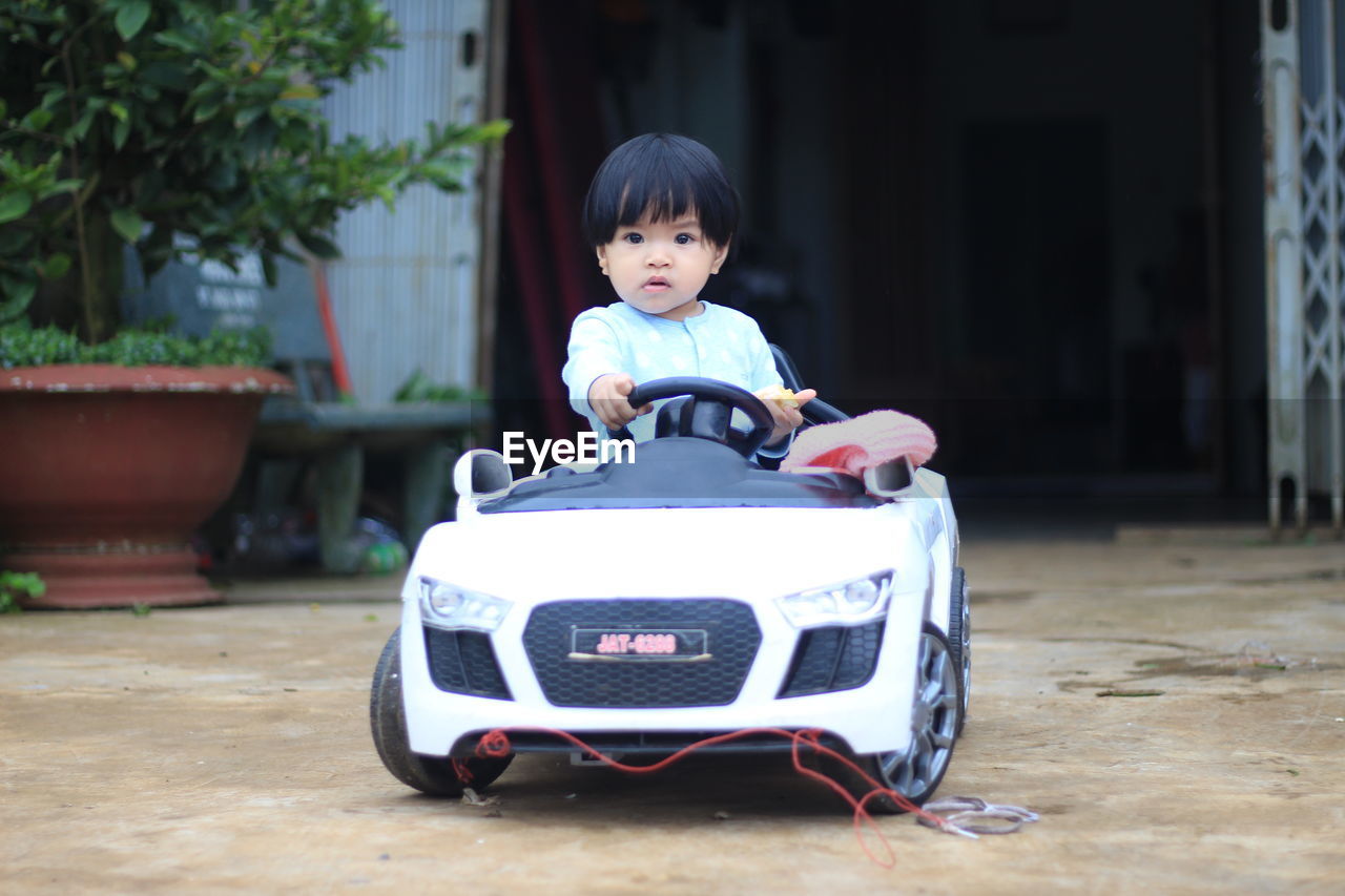 Portrait of cute girl sitting in toy car