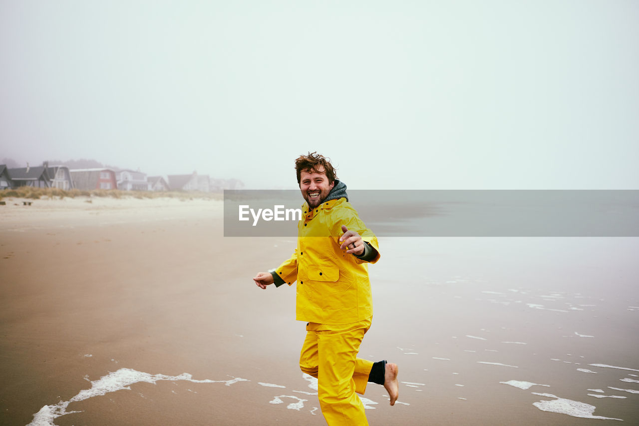 Man running at beach against sky