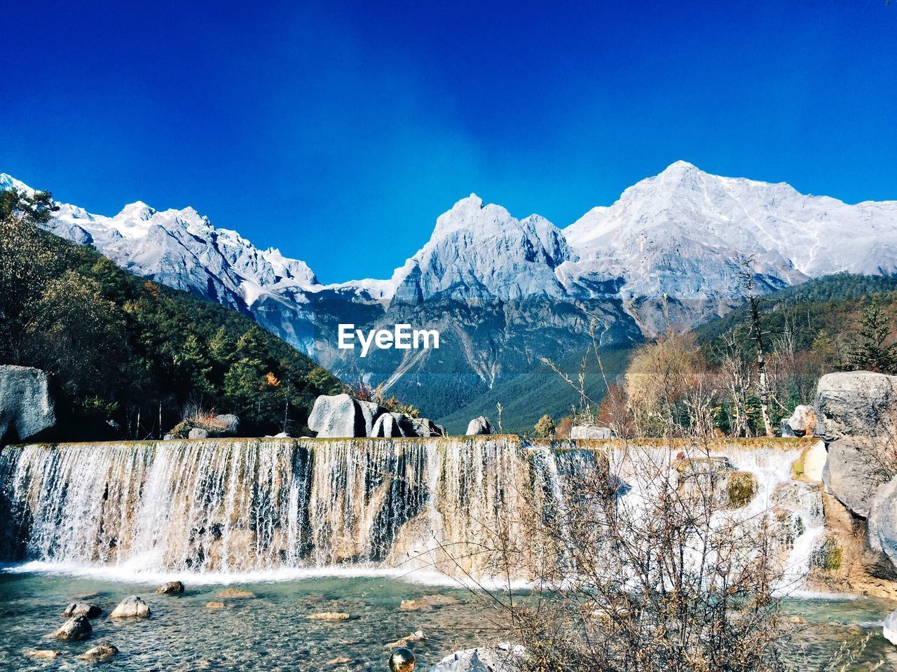 Scenic view of snowcapped mountains against blue sky