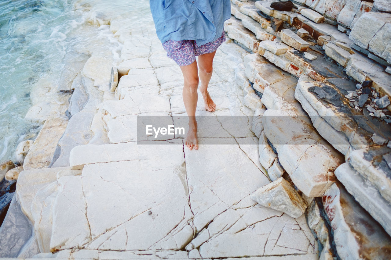 Low section of woman walking on stone steps at beach