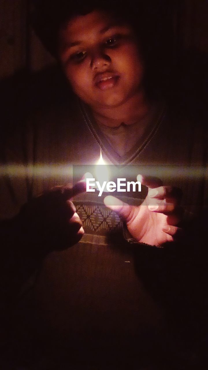 YOUNG MAN HOLDING LIT CANDLE