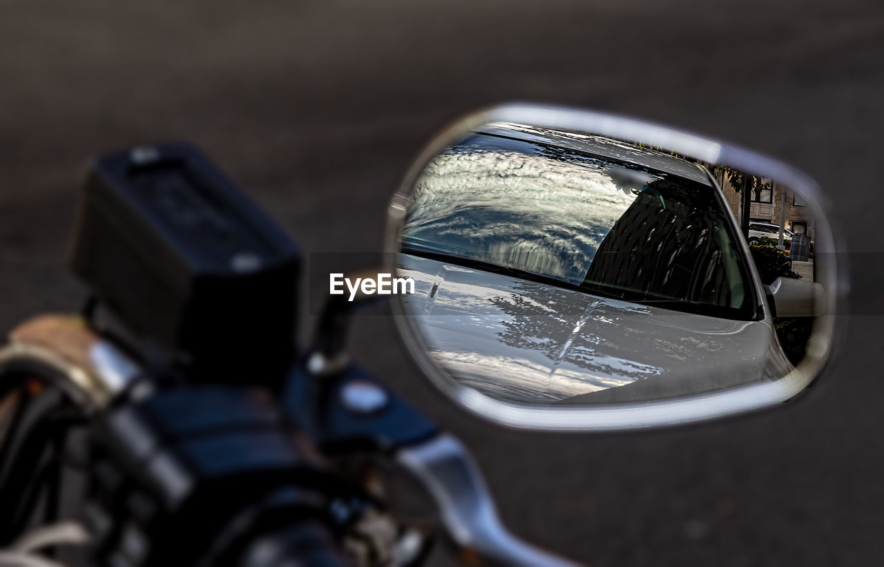 mode of transportation, transportation, vehicle, motorcycle, motor vehicle, land vehicle, car, mirror, close-up, reflection, side-view mirror, headlamp, no people, outdoors, road, automotive mirror, light, selective focus, headlight