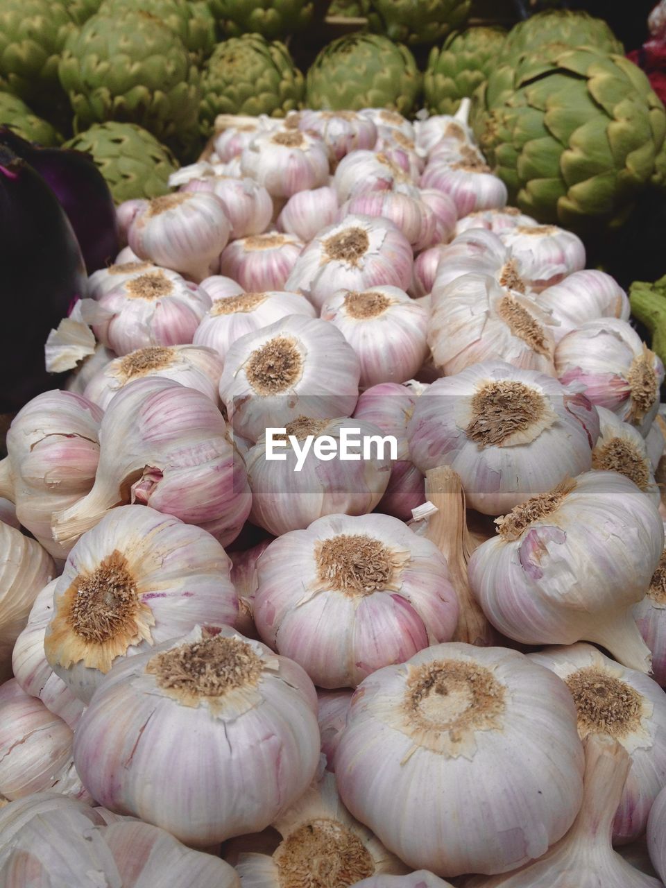 Close-up of garlic bulbs and artichokes for sale at market