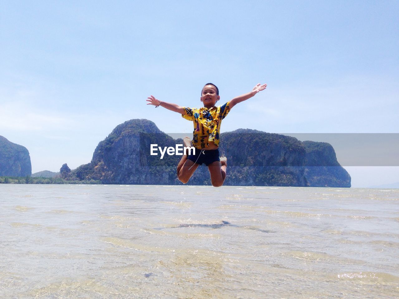 Full length of boy jumping over sea against sky