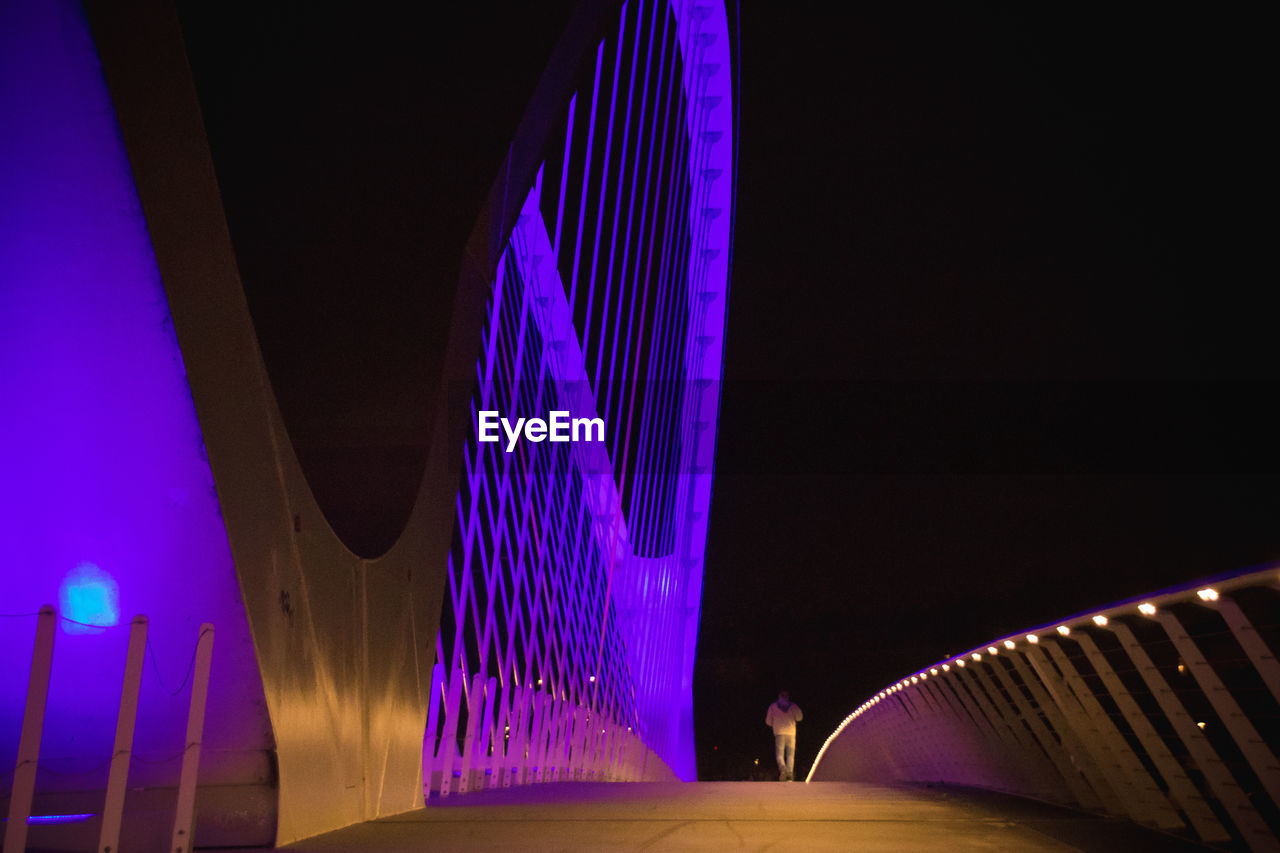 LOW ANGLE VIEW OF ILLUMINATED LIGHTING EQUIPMENT AT NIGHT IN CITY