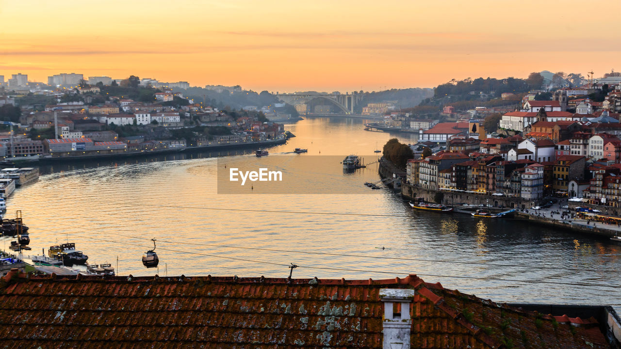 High angle view of river by buildings against sky during sunset