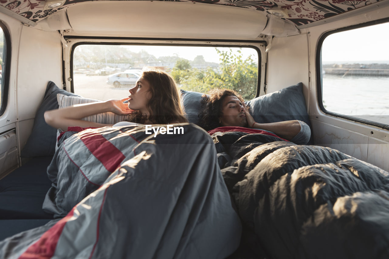 Male and female resting in camping van by seashore
