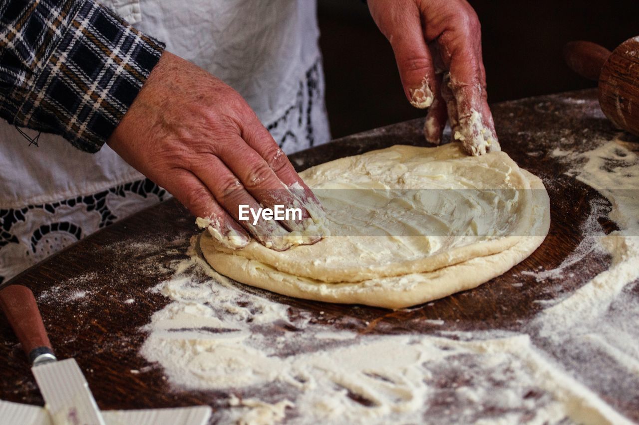 Midsection of man preparing dough in kitchen
