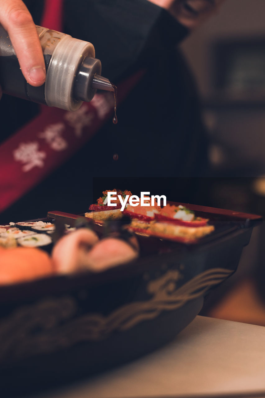 Cropped hand of person preparing sushi on table