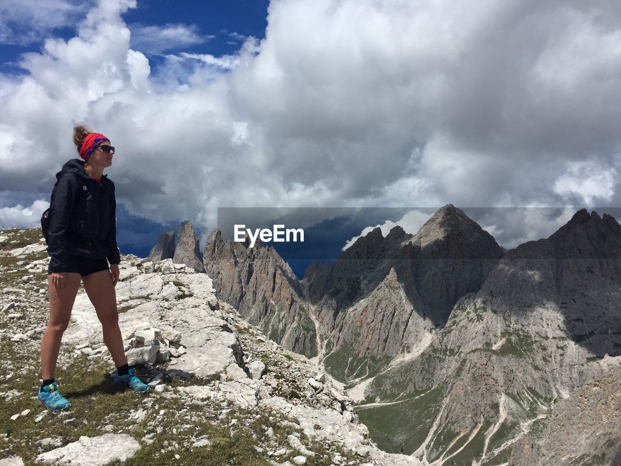 YOUNG WOMAN STANDING ON ROCK AGAINST SKY