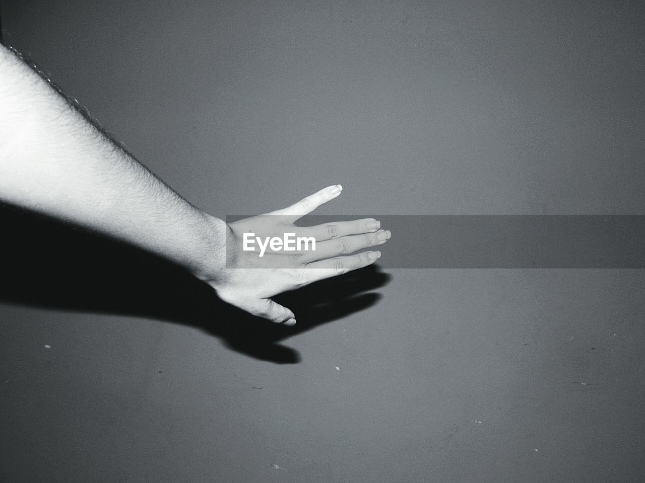 Cropped hand of woman touching wall in darkroom