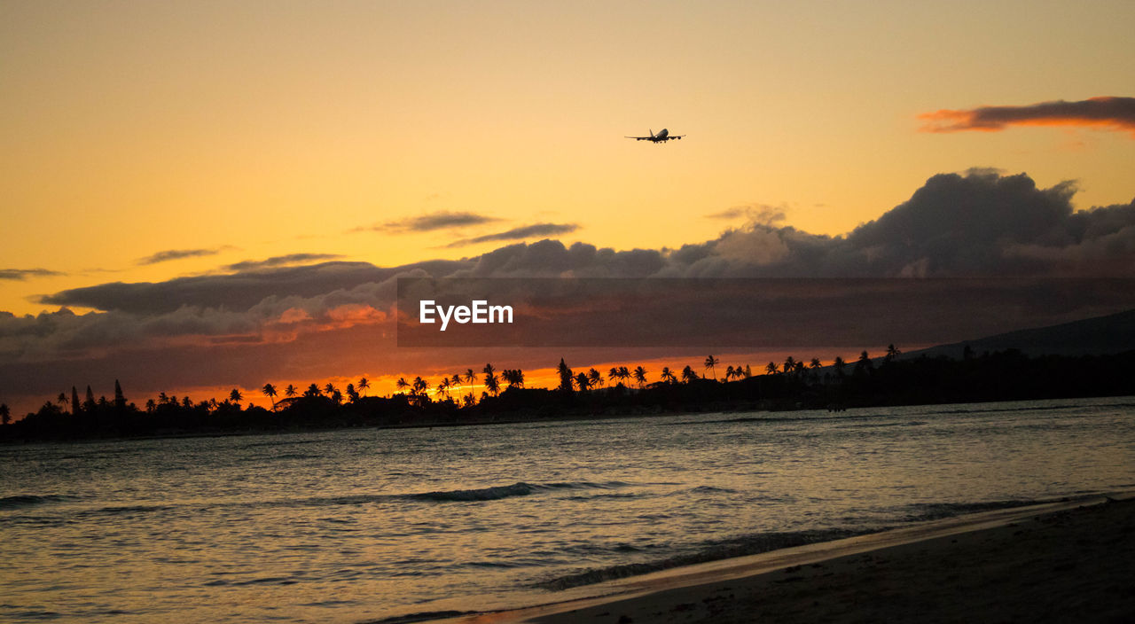 SILHOUETTE OF AIRPLANE FLYING OVER SEA