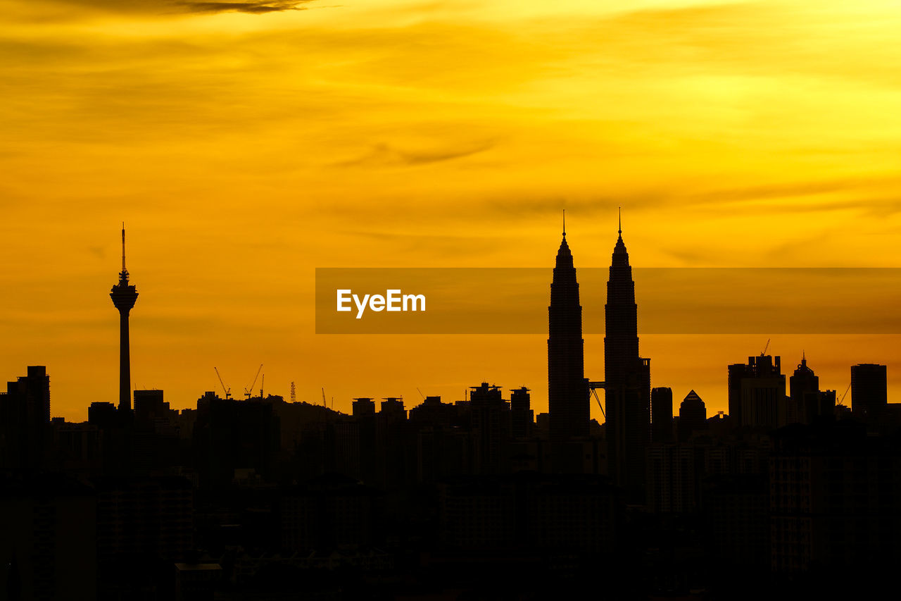 Silhouette petronas tower and kuala lumpur tower against orange sky