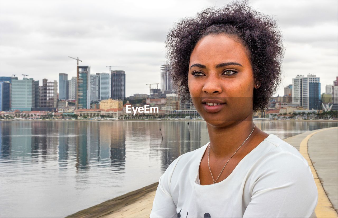 Close-up of smiling young woman by lake
