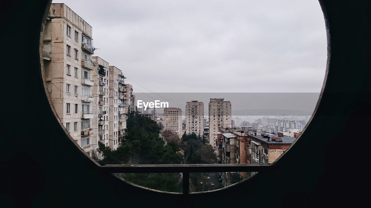 BUILDINGS IN CITY SEEN THROUGH GLASS WINDOW