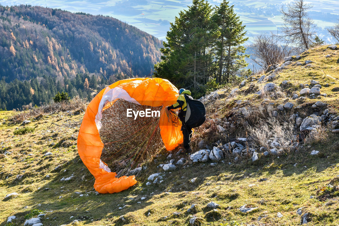 Man removing parachute tangled in bush on mountain