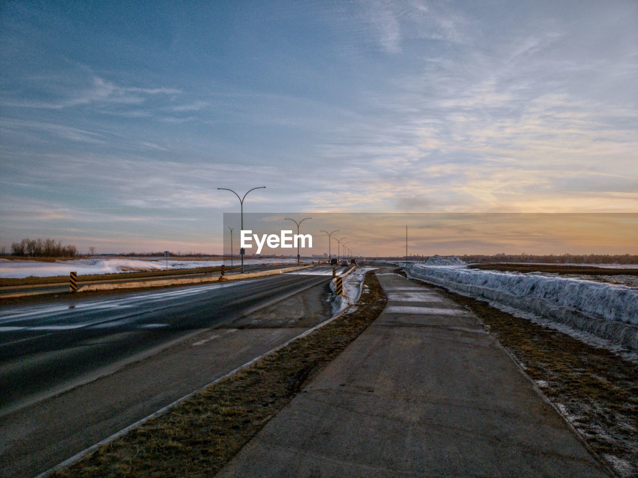 Road by street against sky during sunset