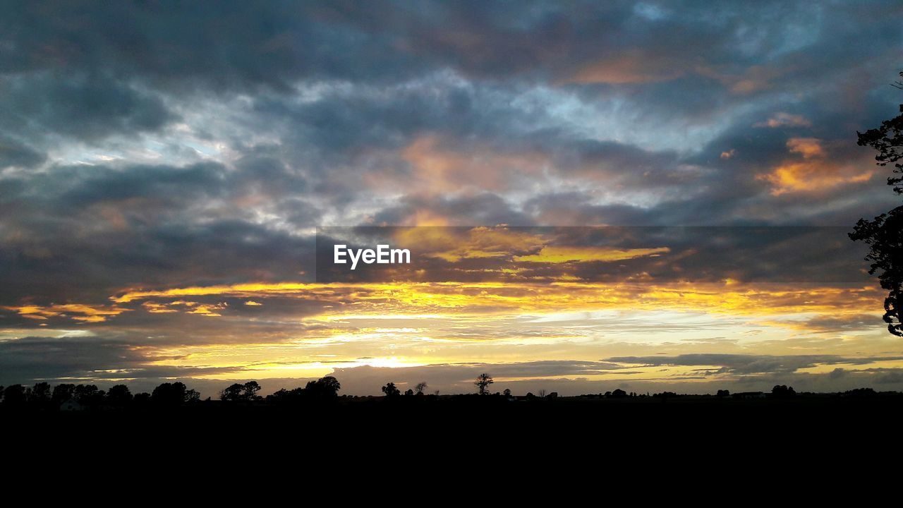 SILHOUETTE OF LANDSCAPE AGAINST DRAMATIC SKY DURING SUNSET
