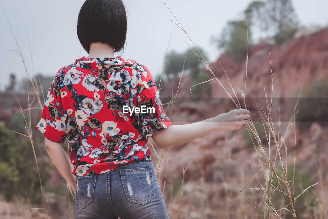 Rear view of woman standing on field against sky