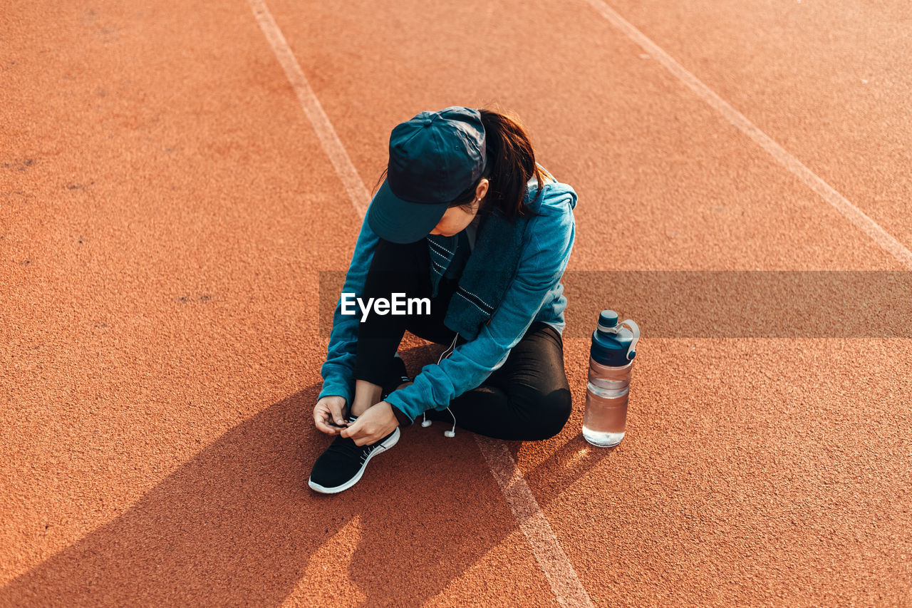 High angle view of woman tying shoelace on sports track