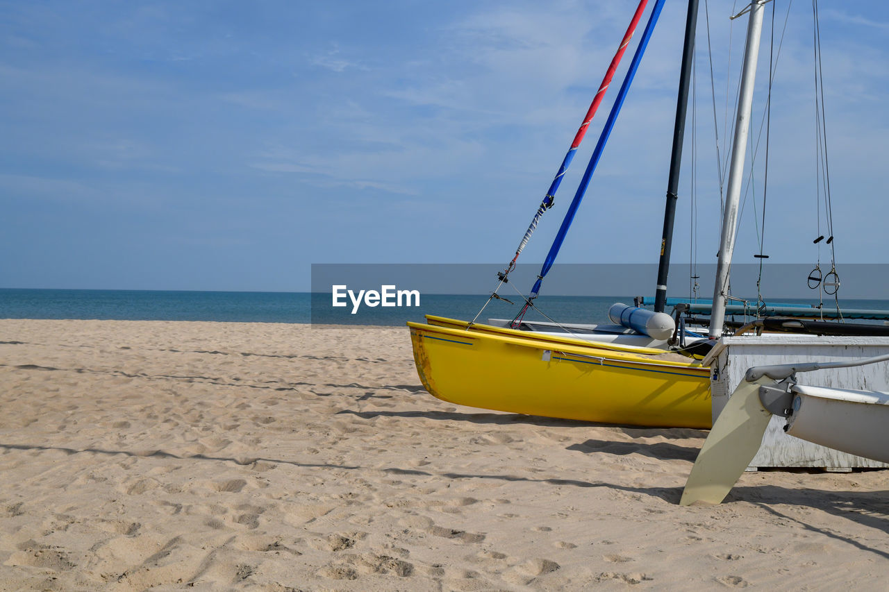 Sailboats moored on beach against sky