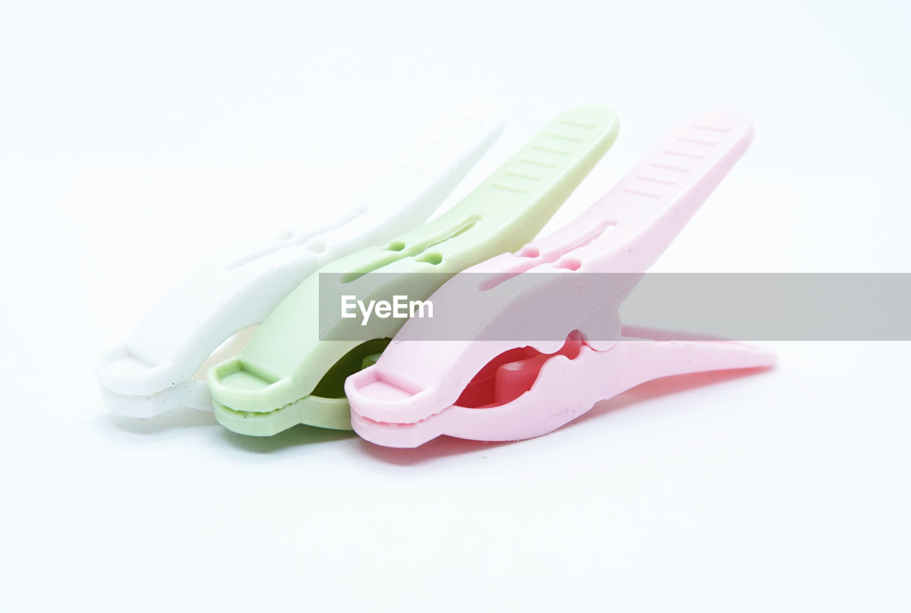 Close-up of colored clothespin s over white background